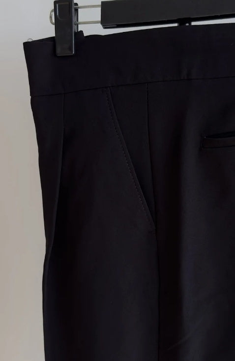 A person standing in an indoor setting wearing high waist slim fit business casual trousers in a green color.