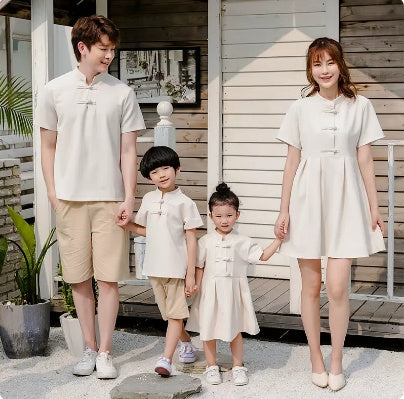 A family of four, including two adults and two children, wearing matching beige outfits with a Hanfu style for the mother and a dress for the daughter.