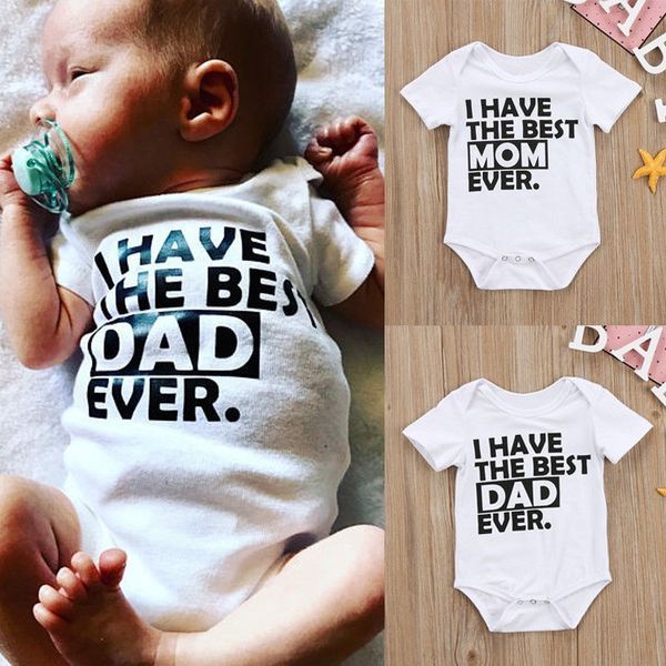 Two newborn babies lying on a furry surface, wearing white rompers with text 'I HAVE THE BEST MOM EVER' and 'I HAVE THE BEST DAD EVER' printed on them.
