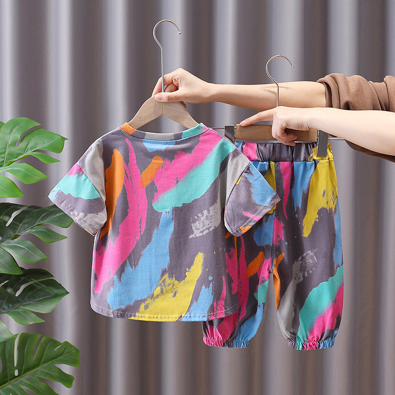Children's summer suit set, with a colorful t-shirt featuring a cartoon character and matching pants, displayed on hangers.