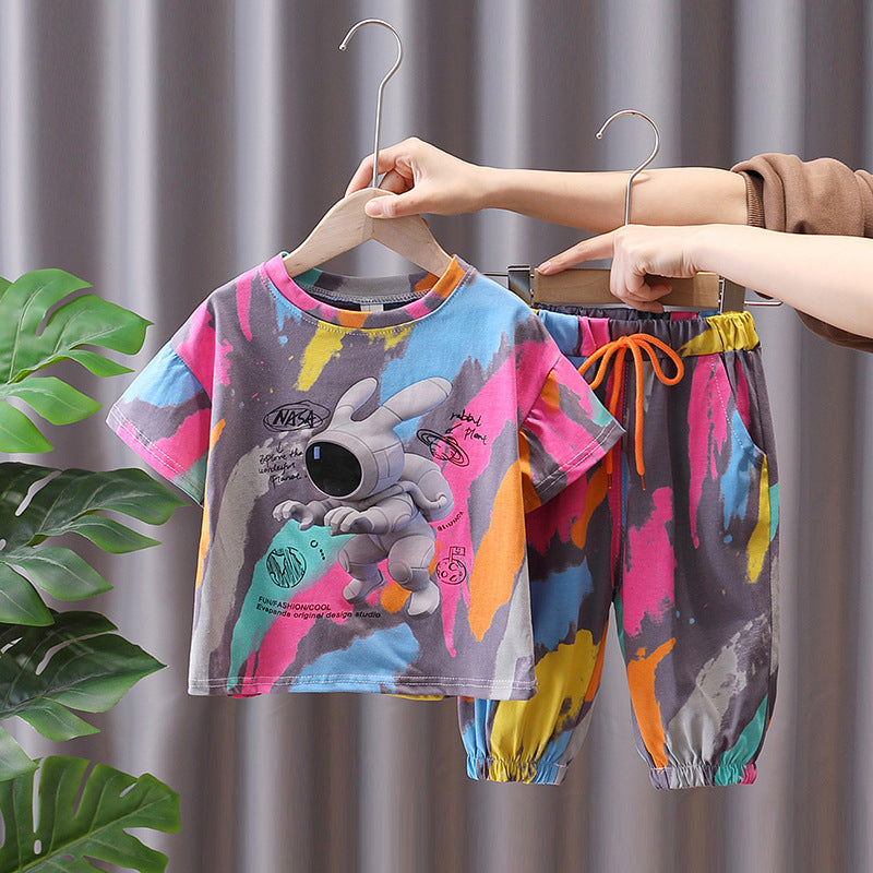 Children's summer suit set, with a colorful t-shirt featuring a cartoon character and matching pants, displayed on hangers.