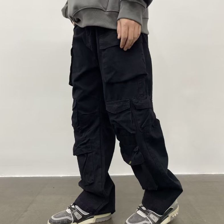 A person standing against a white background, wearing army green straight-leg casual pants with multiple pockets and a pair of sneakers.