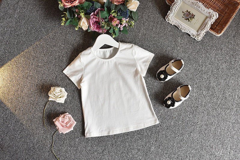 A girls' short-sleeved t-shirt and suspender skirt two-piece suit displayed on a mannequin, with the skirt in a dark green floral pattern and the t-shirt in white.