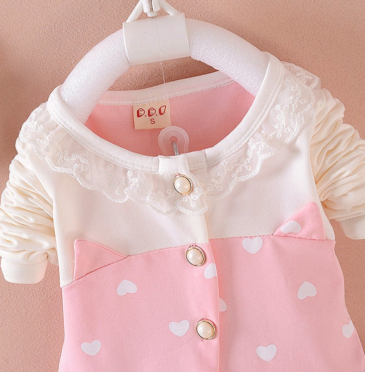 Close-up of BibiCola baby girl tracksuit top showing lace collar, pearl buttons, and soft cotton fabric with heart prints.