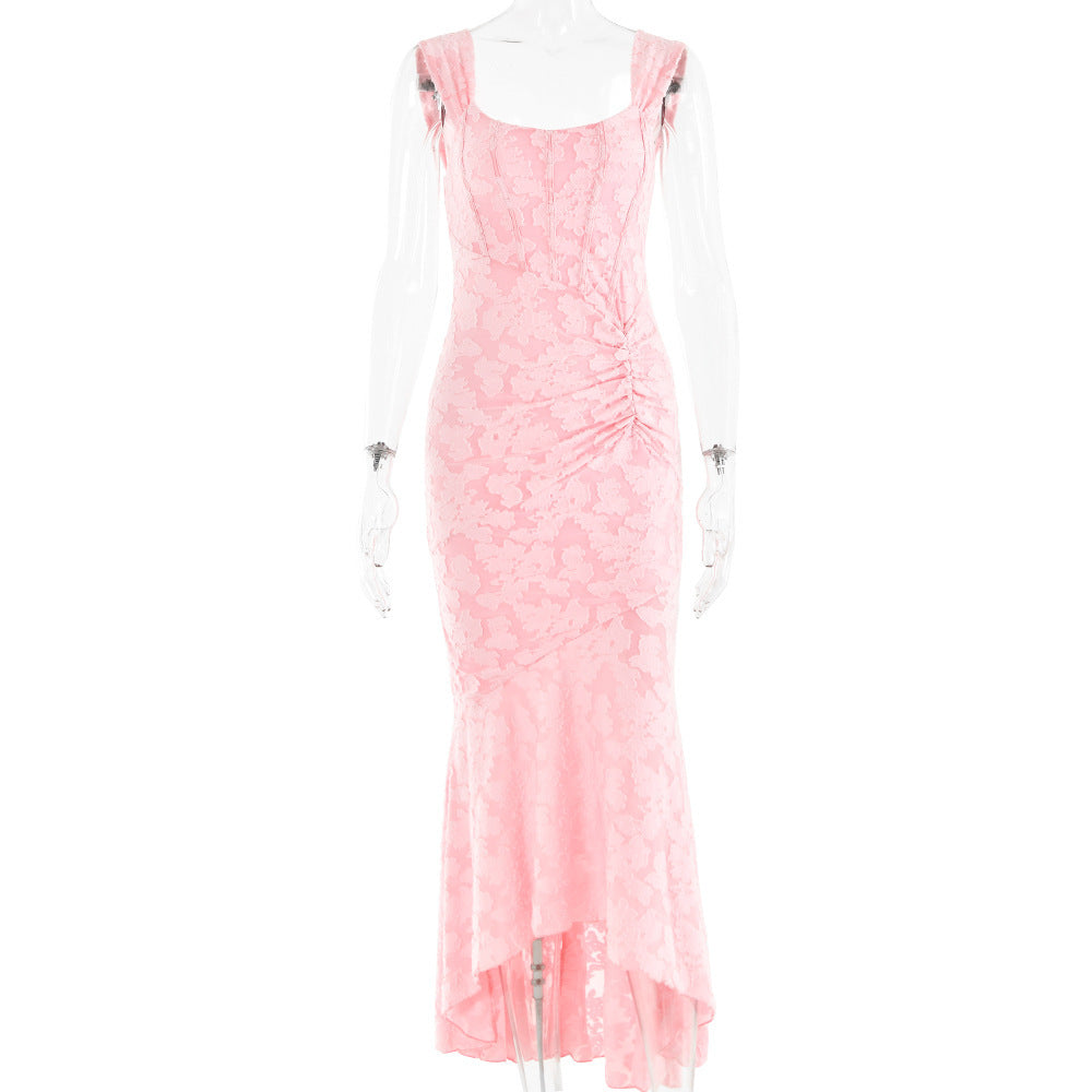 A long, sleeveless, pink evening dress with an off-shoulder neckline and a backless design, featuring a high-waist and suspender skirt.