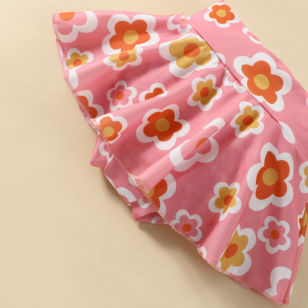 A set of children's clothing including a white sleeveless top with a bow at the neck, a pink skort with a floral pattern, and a matching hairband, displayed against a beige background with decorative elements like flowers and stars.