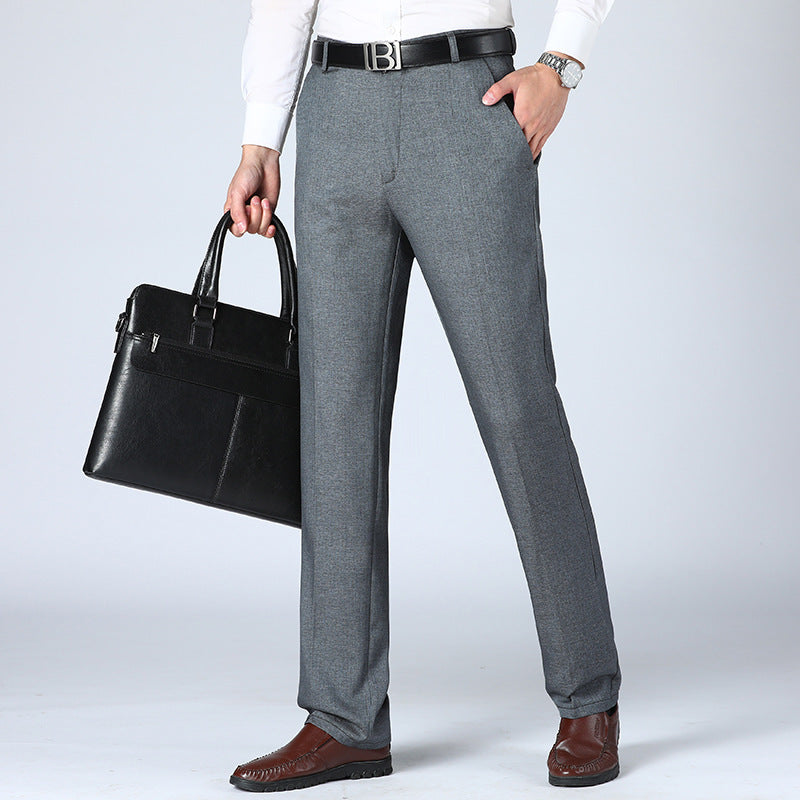 A pair of men's straight-leg suit pants in a light gray color, displayed in a full-length image with a person standing with one hand in a pocket.