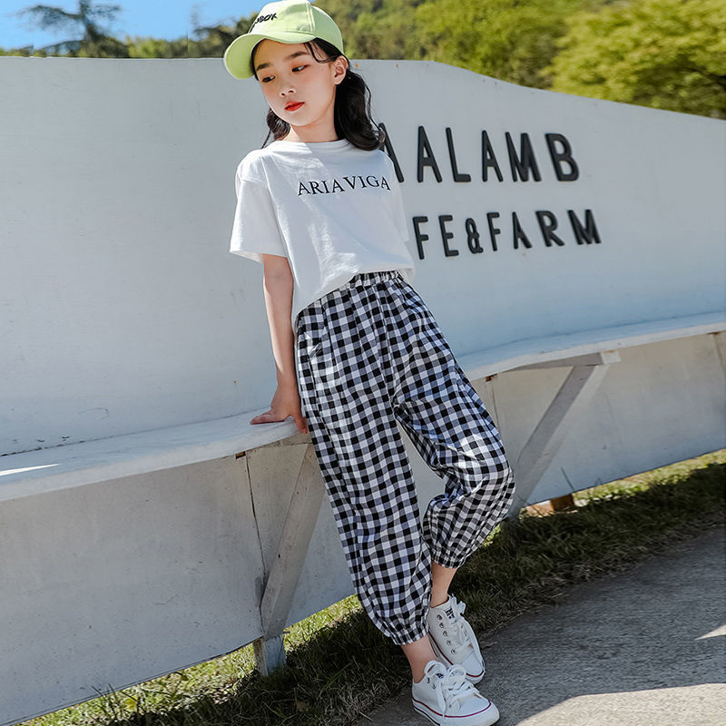 Two girls wearing a summer plaid pants short sleeve suit, one with a white T-shirt and the other with a black T-shirt, both in checkered black and white pants, paired with hats and white sneakers.