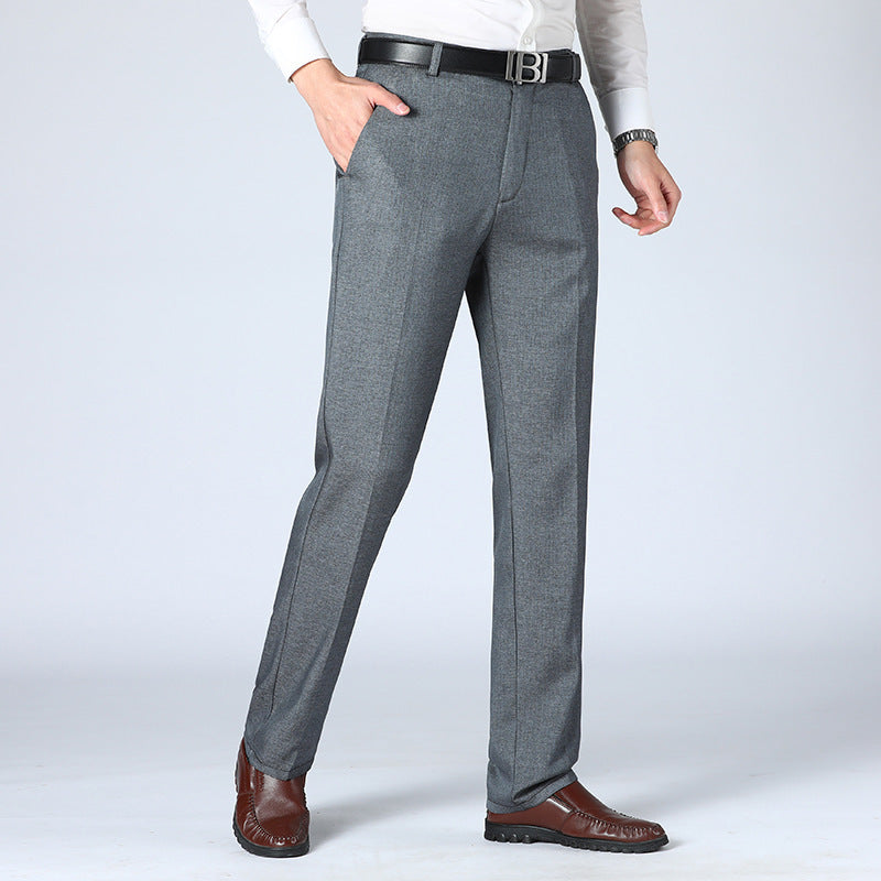 A pair of men's straight-leg suit pants in a light gray color, displayed in a full-length image with a person standing with one hand in a pocket.