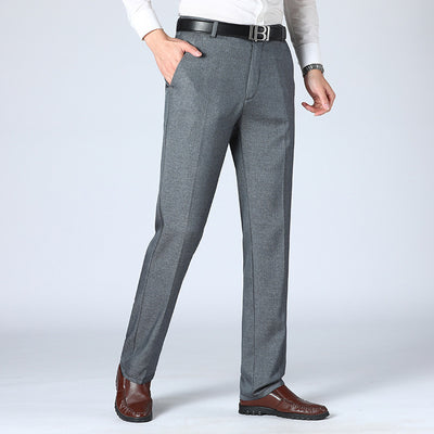 A pair of men's straight-leg suit pants in a light gray color, displayed in a full-length image with a person standing with one hand in a pocket.