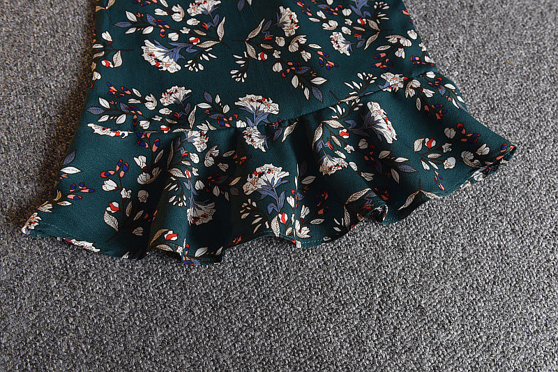 A girls' short-sleeved t-shirt and suspender skirt two-piece suit displayed on a mannequin, with the skirt in a dark green floral pattern and the t-shirt in white.