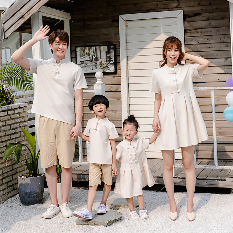 A family of four, including two adults and two children, wearing matching beige outfits with a Hanfu style for the mother and a dress for the daughter.