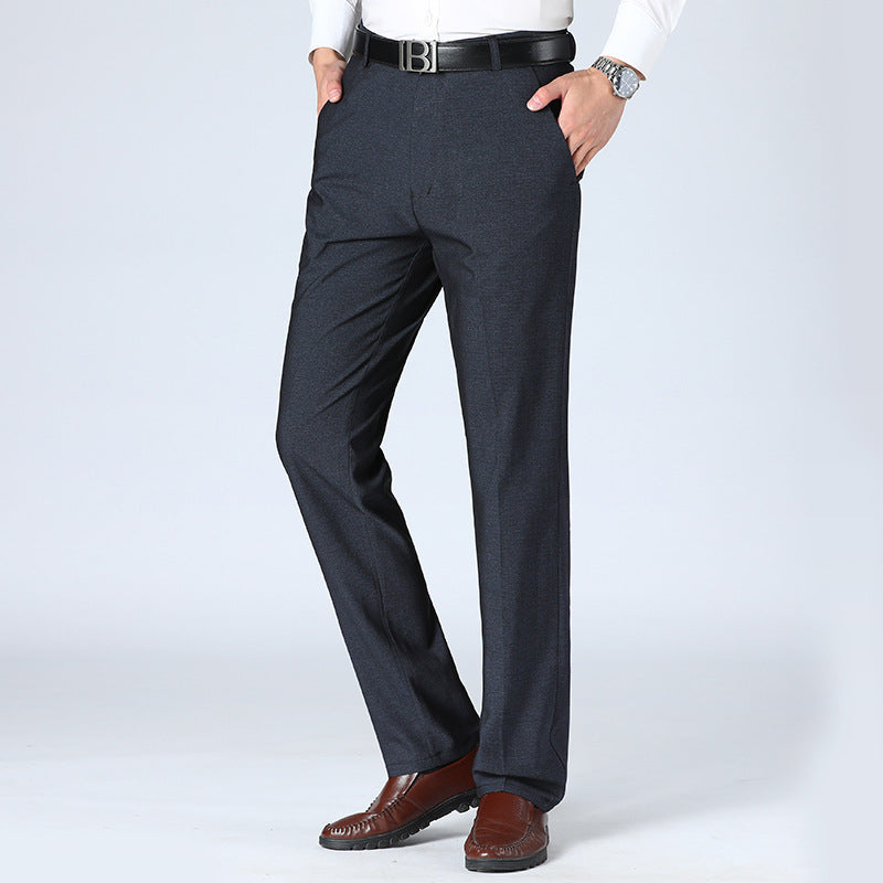 A pair of men's straight-leg suit pants in a light gray color, displayed in a full-length image with a person standing with one hand in a pocket.