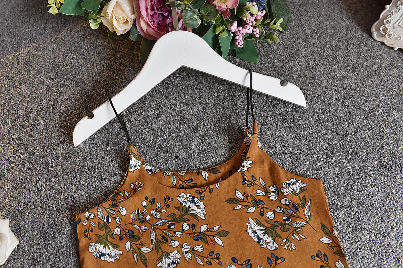 A girls' short-sleeved t-shirt and suspender skirt two-piece suit displayed on a mannequin, with the skirt in a dark green floral pattern and the t-shirt in white.