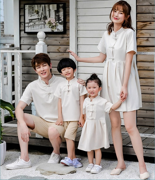 A family of four, including two adults and two children, wearing matching beige outfits with a Hanfu style for the mother and a dress for the daughter.