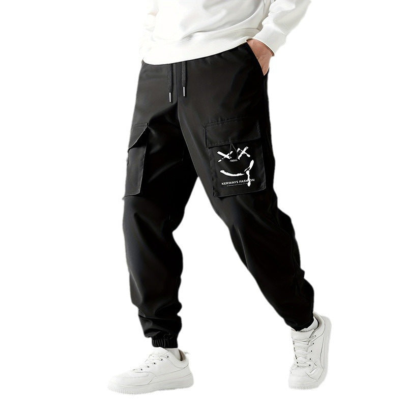 A person wearing black straight-leg ankle-tied overalls casual pants with a mid-waist waist and white sneakers.