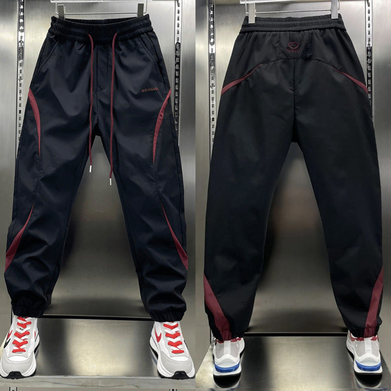Two pairs of ankle banded pants displayed, one in white and one in wine red, both with drawstrings and side stripes, suitable for youth sizes.
