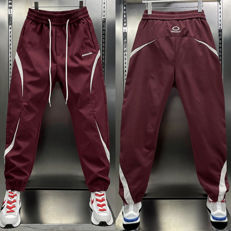 Two pairs of ankle banded pants displayed, one in white and one in wine red, both with drawstrings and side stripes, suitable for youth sizes.