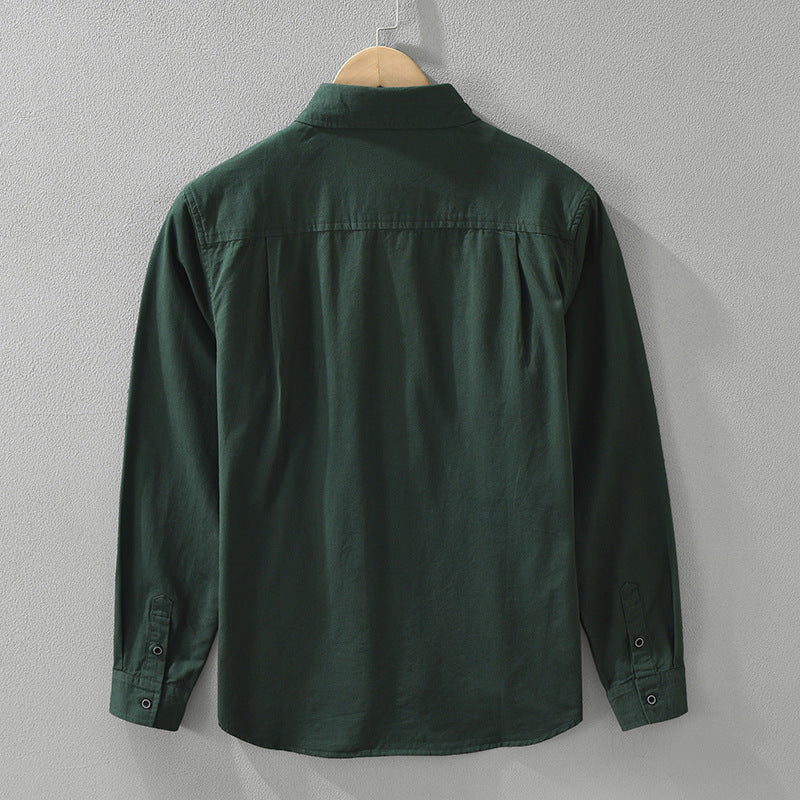 A long sleeve men's shirt in dark green color, displayed on a wooden hanger with a white inner shirt visible.