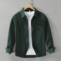 A long sleeve men's shirt in dark green color, displayed on a wooden hanger with a white inner shirt visible.