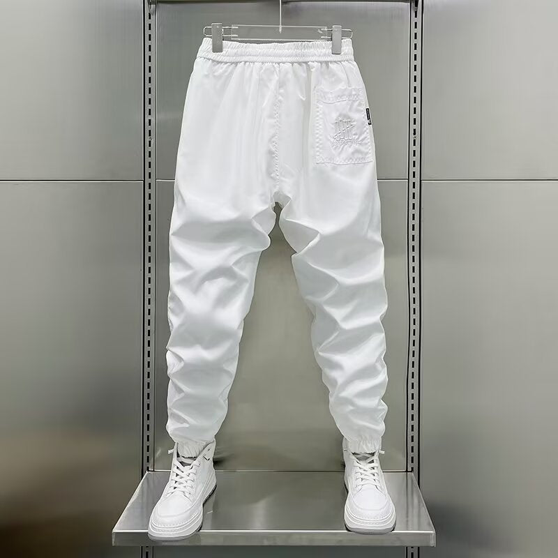 A pair of white men's sports pants with an ankle-tie style displayed on a mannequin.