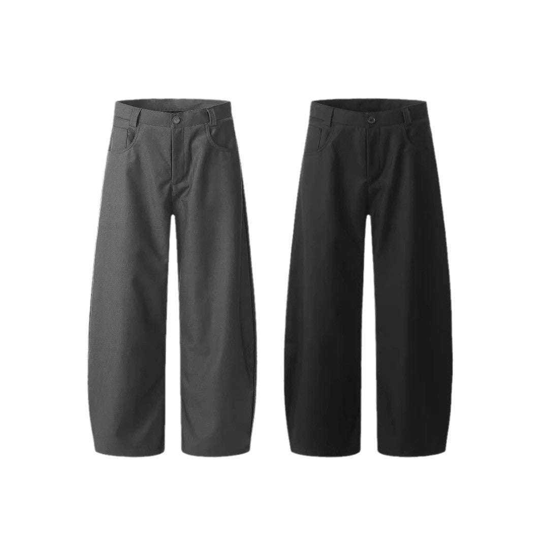 A person standing against a white background, wearing black wide-leg suit pants and a gray sweatshirt.