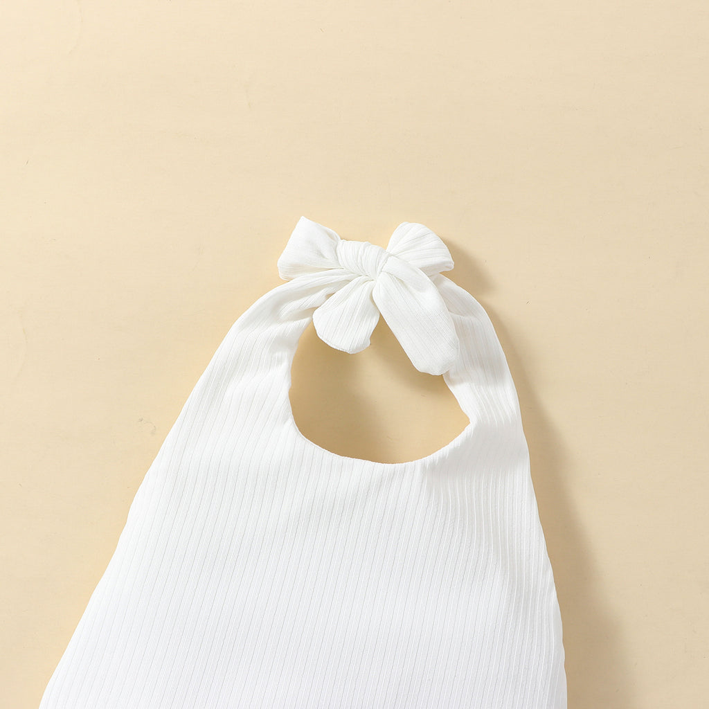 A set of children's clothing including a white sleeveless top with a bow at the neck, a pink skort with a floral pattern, and a matching hairband, displayed against a beige background with decorative elements like flowers and stars.