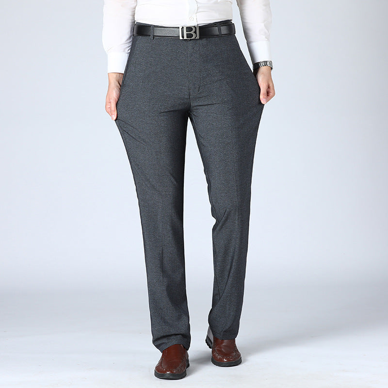 A pair of men's straight-leg suit pants in a light gray color, displayed in a full-length image with a person standing with one hand in a pocket.