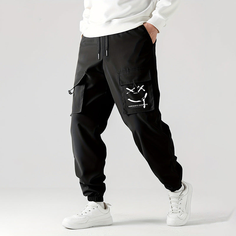 A person wearing black straight-leg ankle-tied overalls casual pants with a mid-waist waist and white sneakers.