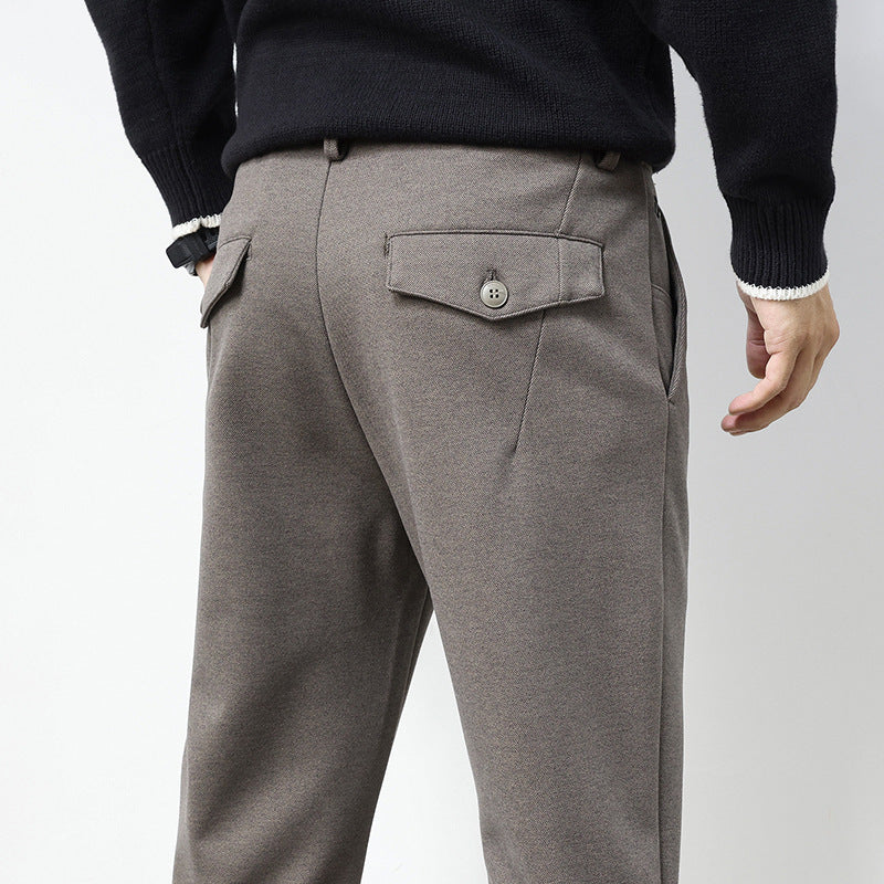 A pair of men's straight-leg casual pants in dark gray color, displayed on a model wearing white sneakers and a black top.