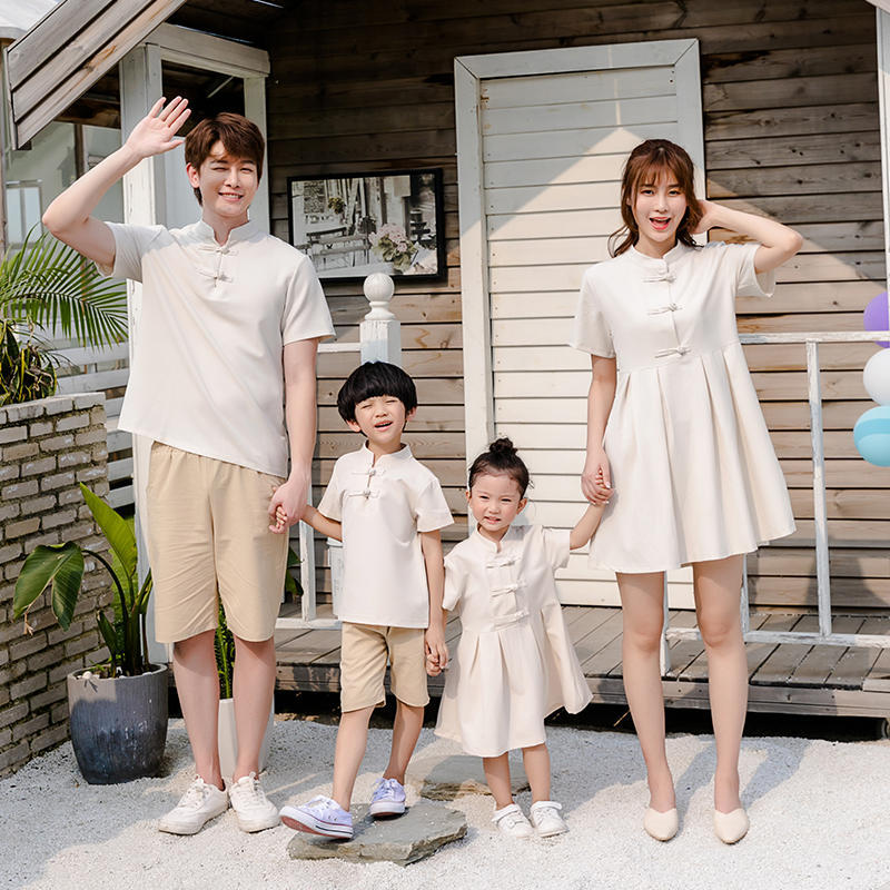 A family of four, including two adults and two children, wearing matching beige outfits with a Hanfu style for the mother and a dress for the daughter.
