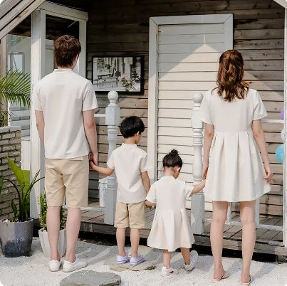 A family of four, including two adults and two children, wearing matching beige outfits with a Hanfu style for the mother and a dress for the daughter.
