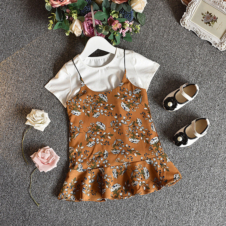 A girls' short-sleeved t-shirt and suspender skirt two-piece suit displayed on a mannequin, with the skirt in a dark green floral pattern and the t-shirt in white.