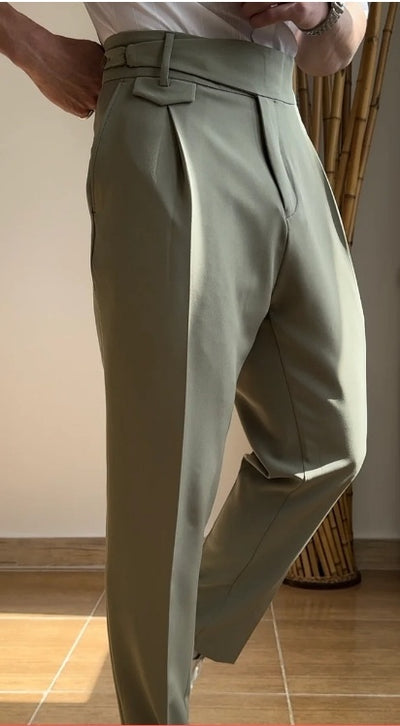 A person standing in an indoor setting wearing high waist slim fit business casual trousers in a green color.